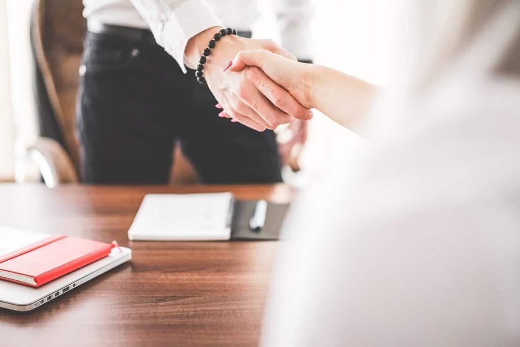 Two business people shaking hands in an office, representing a successful sales follow-up