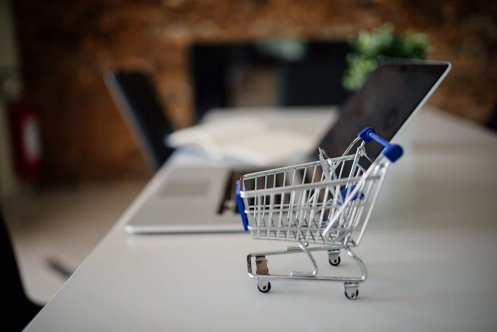 Small shopping cart on a table next to a laptop in an office setting