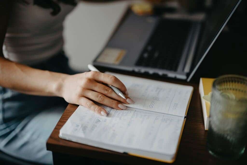 Writing notes at a desk while turning them into a project brief