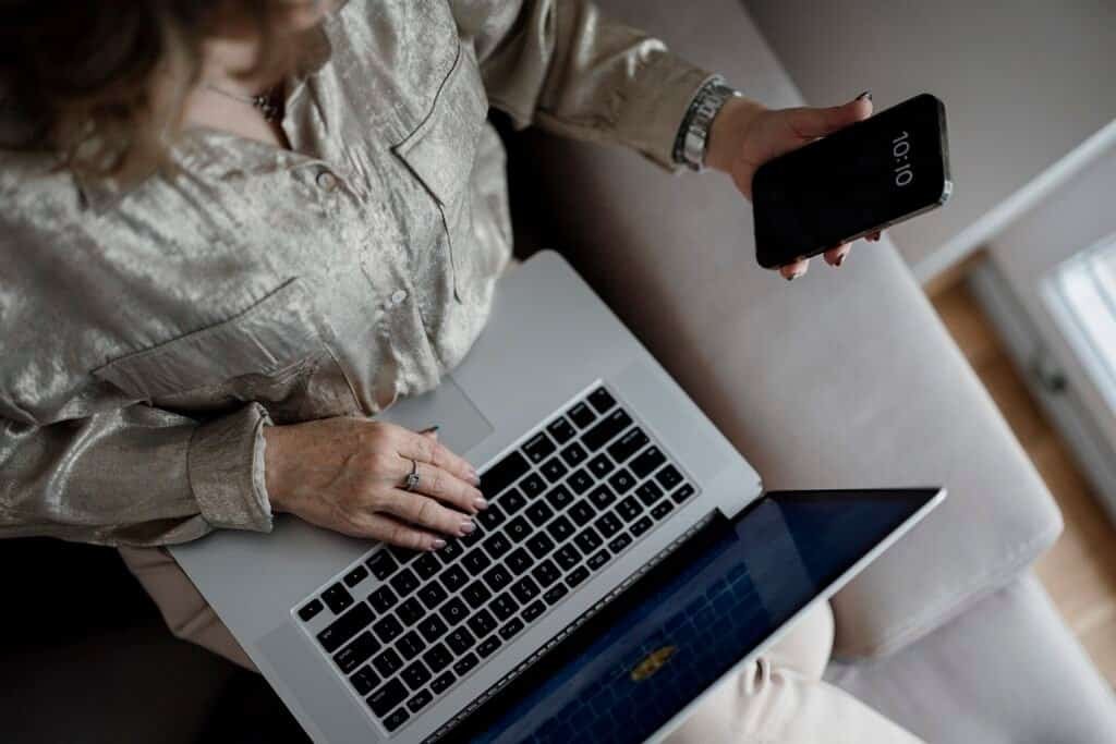 Person working on laptop and smartphone drafting ad campaigns