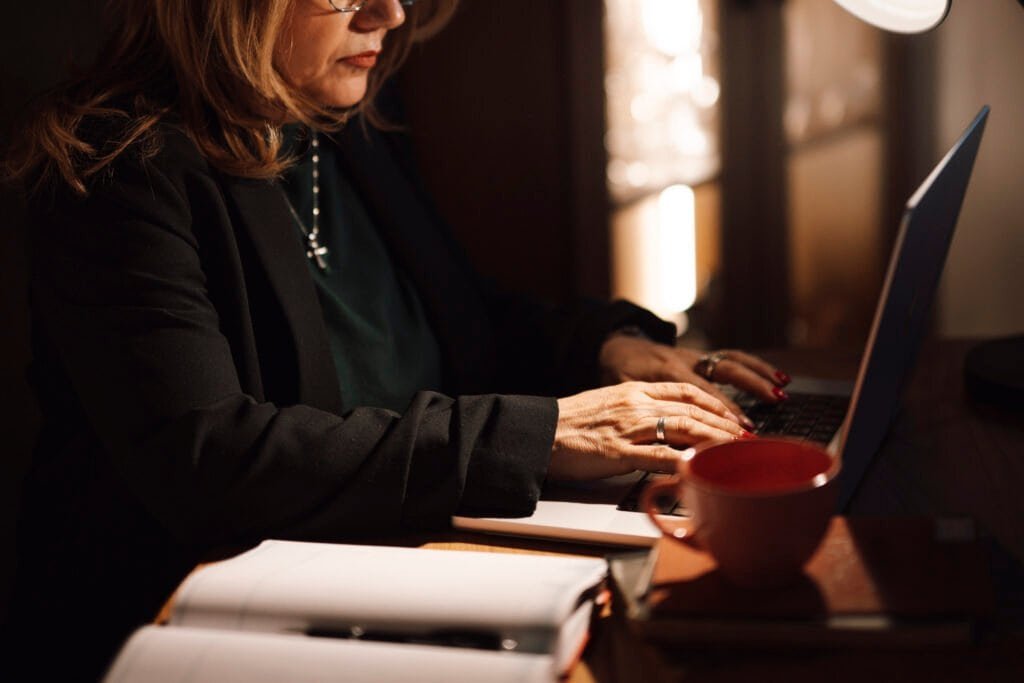 Businesswoman typing on a laptop at a home office desk, representing writing a weekly status report