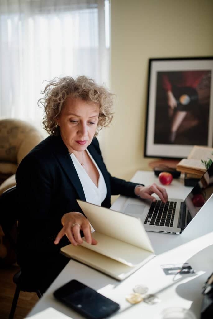 Professional reviewing documents and a laptop while conducting a content audit