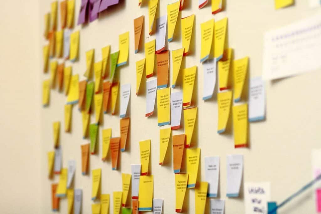 Wall covered in colorful sticky notes from a team brainstorming session, representing a sprint retrospective