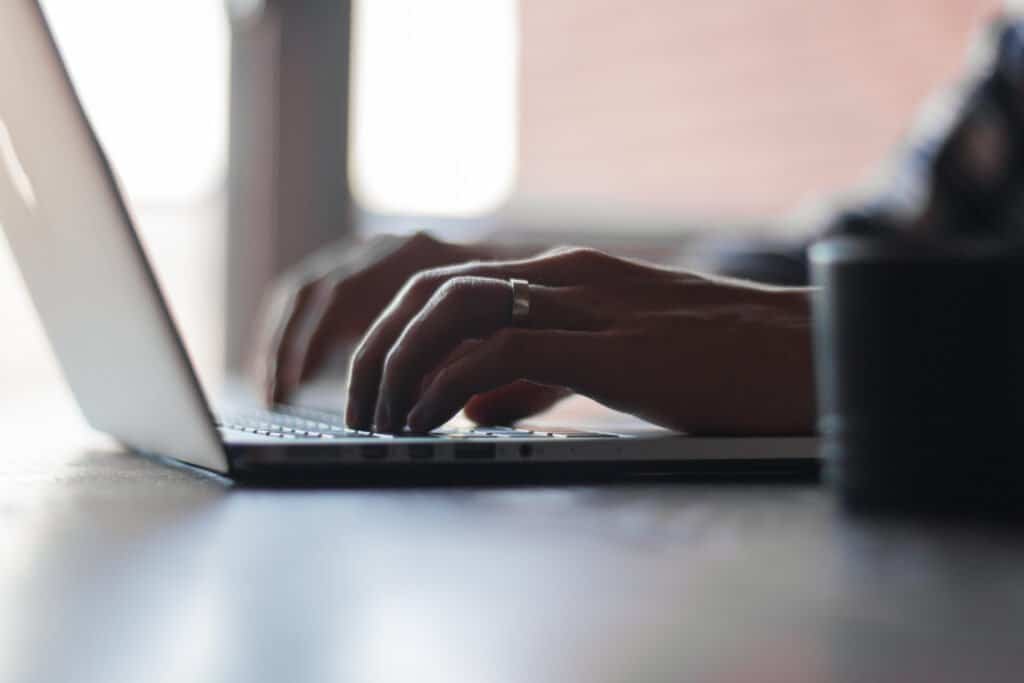 Person typing on a laptop keyboard, representing writing and editing a blog post