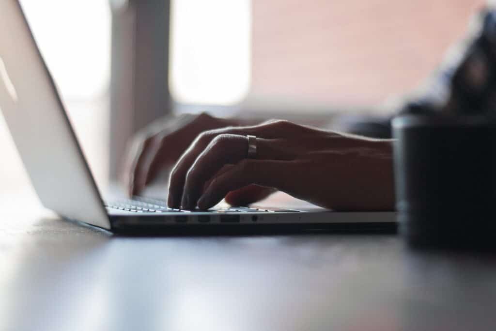 Person typing on a laptop, writing a win-back email sequence to re-engage quiet customers